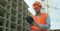 Modern construction engineer or architect in helmet at construction site works with industrial electronic tablet. Close Royalty Free Stock Photo