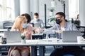 Modern high five at work after lockdown and new normal. Happy millennial man and woman in protective masks touch their