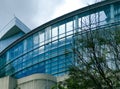 Modern contemporary office building exterior, blue sky with clouds. Architecture exterior is curved, with reflective glass windows Royalty Free Stock Photo