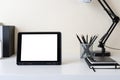 Modern contemporary workspace with mockup blank screen tablet computer and office supplies on white table. Front view of workplace Royalty Free Stock Photo