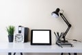 Modern contemporary workspace with mockup blank screen tablet computer and office supplies on white table. Front view of workplace Royalty Free Stock Photo