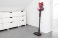 Modern Cordless vacuum cleaner leaning on a wall of a room