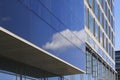 Modern corporate highrise building with glass facade reflecting sky with clouds Royalty Free Stock Photo