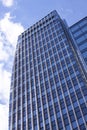 Modern corporate highrise office building reflecting sky with clouds seen from below Royalty Free Stock Photo