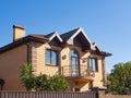 Modern cottage with forgery balcony and brick facade. Blue sky background