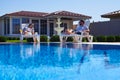 Modern couple getting tan under the sun near pool