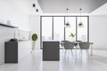 Modern cozy bright furnished kitchen with big windows, chairs, table and lamps, white concrete floor and an empty wall, city view Royalty Free Stock Photo
