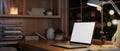 Modern and cozy home office workspace at night with a white-screen laptop computer on a wood table Royalty Free Stock Photo