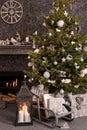 Modern cozy interior in white and gray shades with a fireplace and decorated Christmas tree. Royalty Free Stock Photo