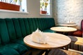 A modern cozy restaurant with colorful upholstered chairs and comfortable sofas. There are napkins and cutlery on the table. Table Royalty Free Stock Photo