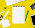 Modern creative bright yellow office desk with laptop, smartphone and other accessories - calculator, scissors, ruler, pen. Blank