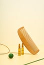 Modern Creative still life, balance photo. Cosmetic ampoules with serum for hair growth, restoration. Hair comb, green props on a