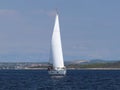 A modern cruise sailing yacht with a Bermuda sloop-type rig goes past the green coast of the Croatian Riviera on a sunny summer da