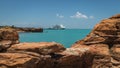Modern cruise ship tied up to jetty surrounded by a turquoise sea at Broome in Western Australia framed by ochre coloured rocks