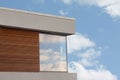 Modern cube house with wooden panels and blue sky with white clouds reflecting