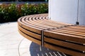 Modern curved shaped brown wooden outdoor design bench in green zone