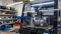 Modern 3d printer creating a complex gray object in a workshop with tools nearby Royalty Free Stock Photo