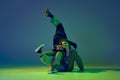 Modern dance concept. Energetic couple of two young woman dancing contemporary dance on gradient blue-green background Royalty Free Stock Photo