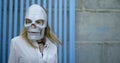 Modern dance of a plastic girl in a paper, polygonal art mask in the form of a skull. She stands against a stone wall Royalty Free Stock Photo