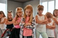 Modern dancers. Group of confident little girls keeping arms crossed, making serious faces and looking at camera while