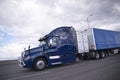 Modern dark blue semi truck with trailer and storage unit