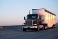Dark big rig semi truck with bulk trailer running on highway in Royalty Free Stock Photo
