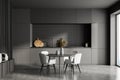 Modern dark grey kitchen interior, dining area with panoramic windows. Furnished by table and chairs for eating, black wooden Royalty Free Stock Photo