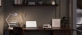 Modern dark office working space at night with laptop mockup on table against the black wall Royalty Free Stock Photo