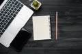 Modern dark wood office desk table with laptop, smartphone and other supplies. Blank notebook page for input the text in the Royalty Free Stock Photo