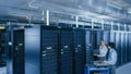 In the Modern Data Center: Engineer and IT Specialist Work with Server Racks, on a Pushcart Equipm Royalty Free Stock Photo