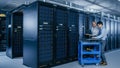 In the Modern Data Center: Engineer and IT Specialist Work with Server Racks, on a Pushcart Equipm Royalty Free Stock Photo
