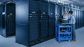 In the Modern Data Center: Engineer and IT Specialist Work with Server Racks, on a Pushcart Equipm Royalty Free Stock Photo