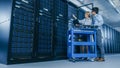 In the Modern Data Center: Engineer and IT Specialist Work with Server Racks, on a Pushcart Equipm Royalty Free Stock Photo