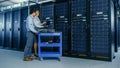 In the Modern Data Center: Engineer and IT Specialist Work with Server Racks, on a Pushcart Equipm Royalty Free Stock Photo