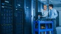 In the Modern Data Center: Engineer and IT Specialist Work with Server Racks, on a Pushcart Equipm Royalty Free Stock Photo