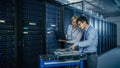 In the Modern Data Center: Engineer and IT Specialist Work with Server Racks, on a Pushcart Equipm Royalty Free Stock Photo
