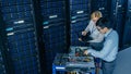 In the Modern Data Center: Engineer and IT Specialist Work with Server Racks, on a Pushcart Equipm Royalty Free Stock Photo