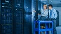 In the Modern Data Center: Engineer and IT Specialist Work with Server Racks, on a Pushcart Equipm Royalty Free Stock Photo