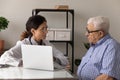 Young woman physician explain aged man therapy details using laptop