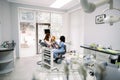 Modern dentist`s office. Mother and little daughter having a regular check up and talking with their dentist, young