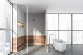 Modern design bathroom interior with shower cabin, white oval bathtub, bronze faucets. Panoramic window with skyscrapers city view Royalty Free Stock Photo