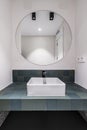 a modern designed bathroom with green tiles porcelain sinks circular mirror white