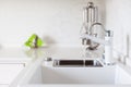 Modern designer chrome water tap over white kitchen sink Royalty Free Stock Photo