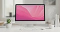 Modern desktop computer displaying vibrant pink abstract wallpaper on minimalist desk Royalty Free Stock Photo