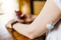 Woman checking glucose level and dosing insulin using insulin pump and remote sensor on her hand