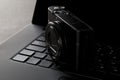 Modern digital camera on laptop keyboard on black desk in office, digital photography or image processing concept