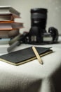 Modern digital SLR camera on the table next to a stack of books, and in the foreground a notebook and pencil. Royalty Free Stock Photo