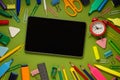 Modern digital tablet on a green background among office and school supplies. School office supplies on a desk with copy space. Royalty Free Stock Photo