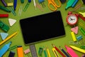 Modern digital tablet on a green background among office and school supplies. School office supplies on a desk with copy space. Royalty Free Stock Photo