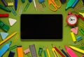 Modern digital tablet on a green background among office and school supplies. School office supplies on a desk with copy space. Royalty Free Stock Photo